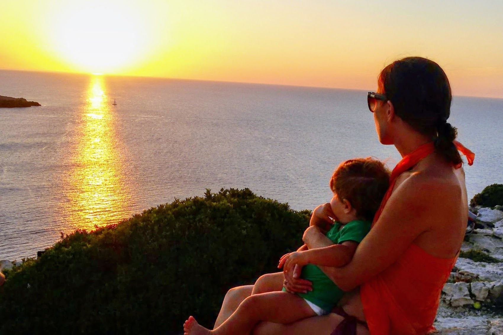 A mother and young boy enjoying the sunset together at the Cavalleria lighthouse on the north coast of Menorca.