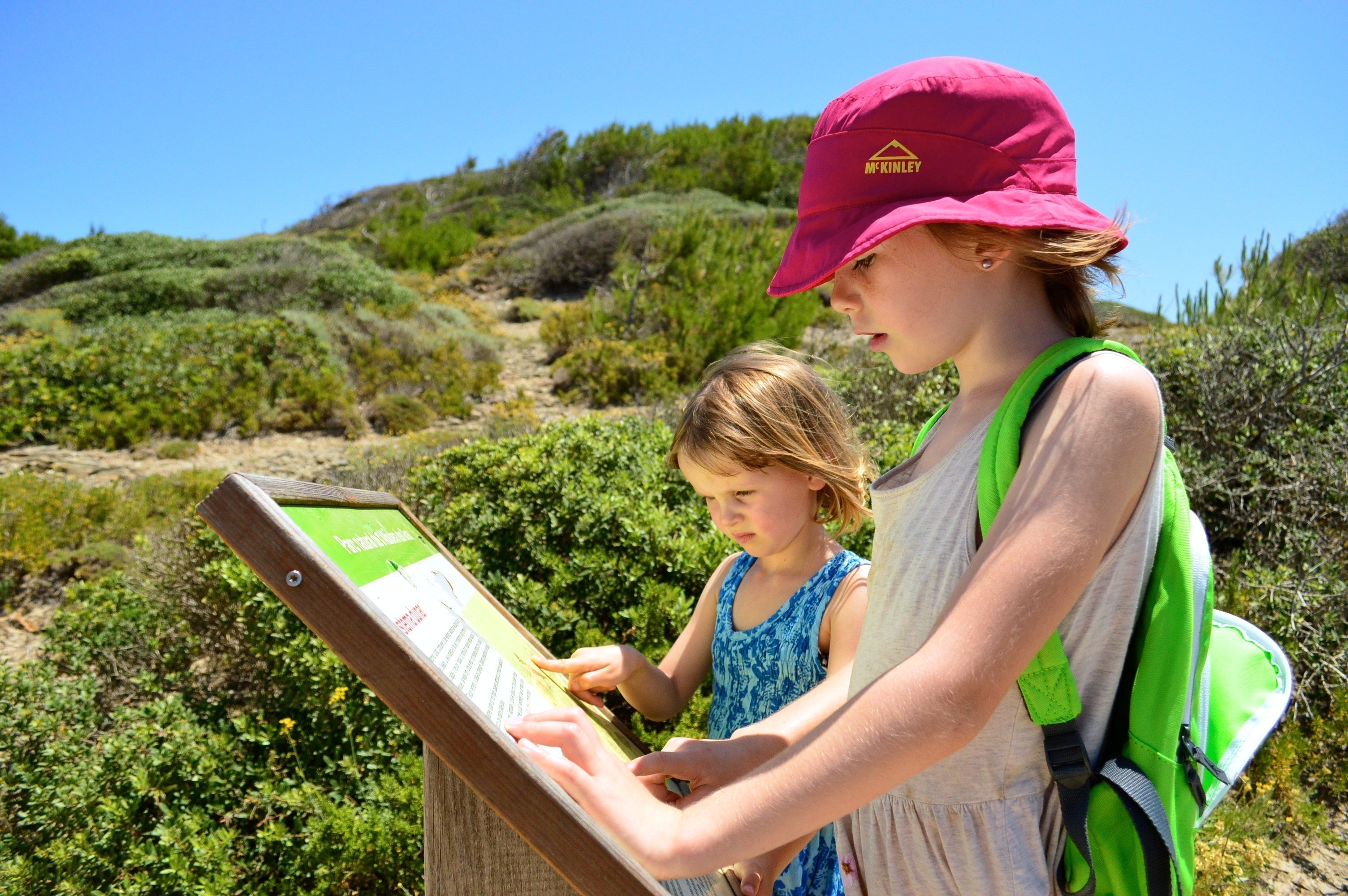 Two girls studying information on a sign located in Menorca's Albufera des Grau, a nature reserve right that touches the Mediterranean Sea