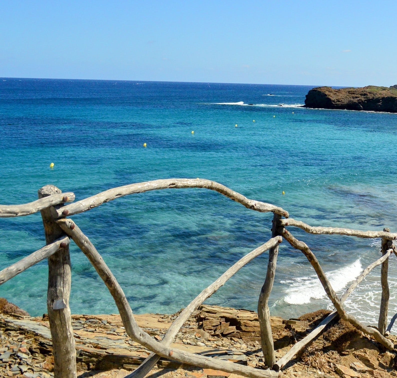 A wild olive wood barrier along the Cami de Cavalls trail, protecting hikers from the high cliff above the blue waters of Menorca's north coast.