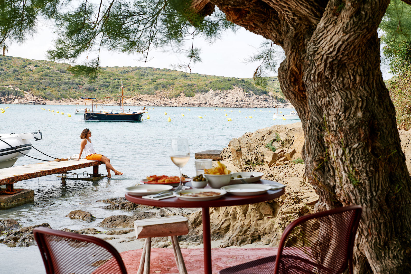 A table set seaside for two, overlooking the bobbing boats and calm waters of Es Grau, Menorca's wonderful north coast fishing village.